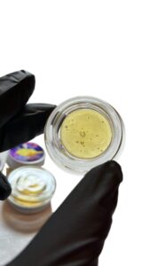 "Fresh pressed rosin for sale in glass concentrate jar showing light gold color and glossy texture"